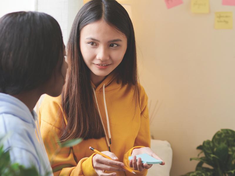 Student holding notepad and pencil counseling fellow student