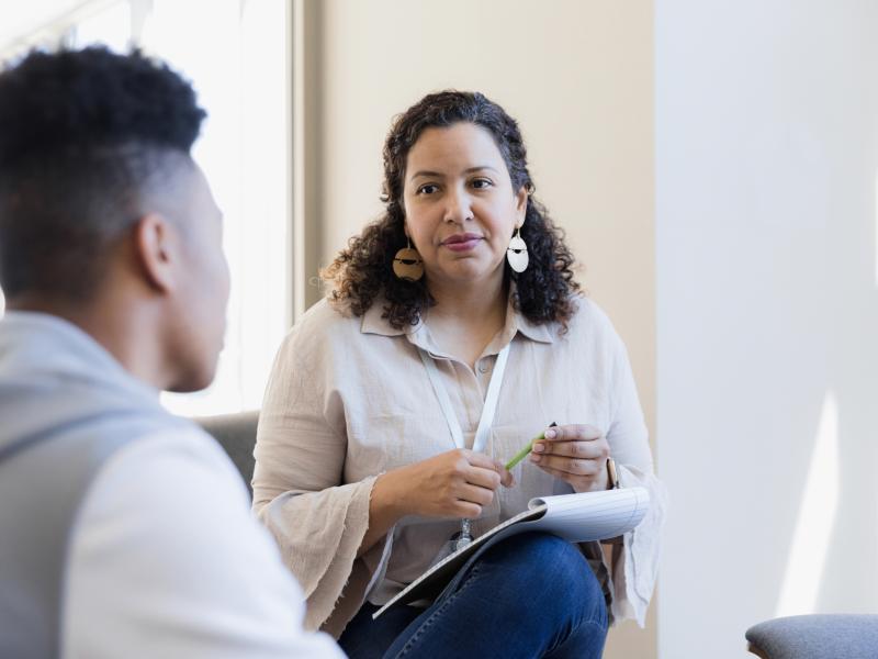 Staff member with notebook and pen counseling student